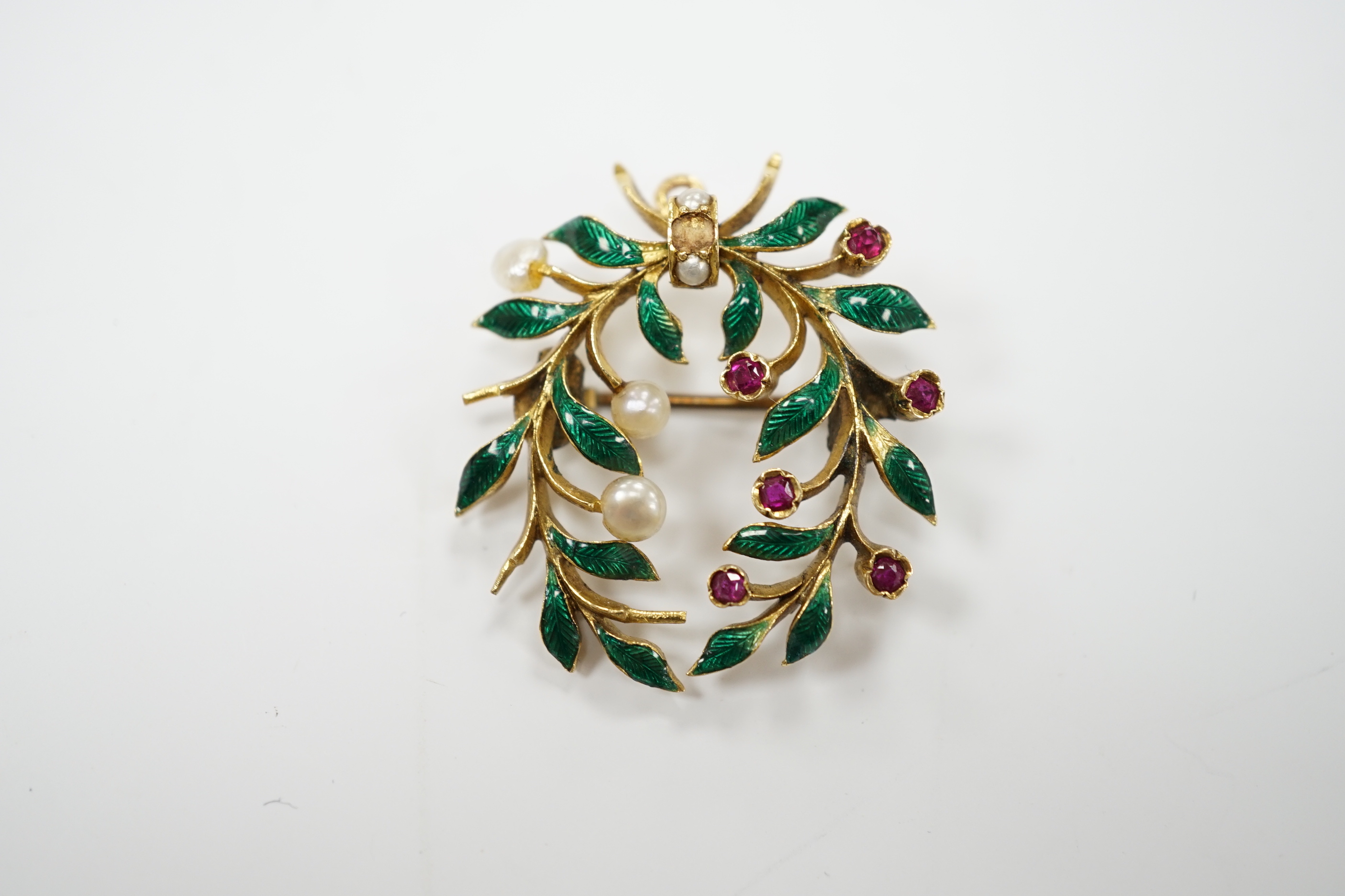 A yellow metal, green enamel, ruby and seed pearl cluster set wreath pendant brooch, 29mm, gross weight 6.9 grams.